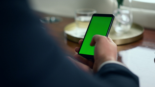 男人手滚动绿色智能手机屏幕特写视频