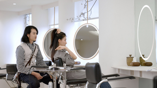 女顾客边梳理自己头发边和发型师交流视频