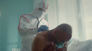 医生戴着防护服面罩用听诊器检查感染患者的背部11秒视频