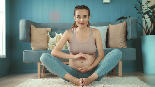 孕妇在家坐着做瑜伽视频