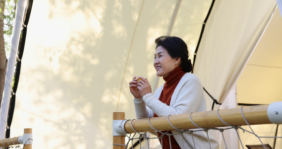 一个中老年女人倚靠着栏杆喝茶视频