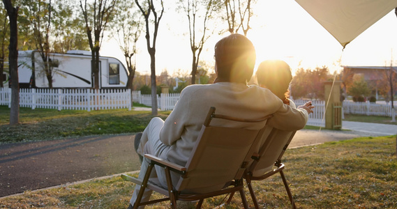 中老年夫妻并肩坐在房车露营地天幕下看夕阳视频