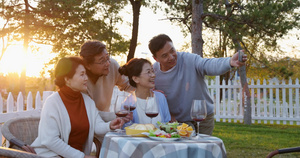 夕阳下中老年朋友在庭院里聚会喝酒拍照片17秒视频