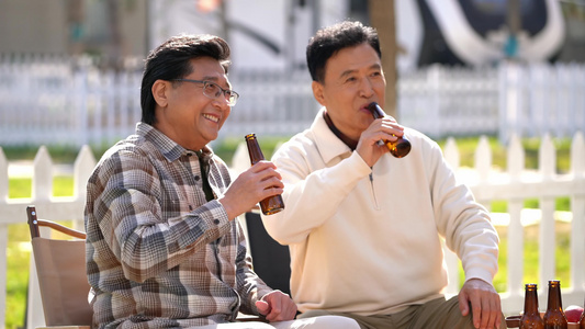 两个老年男人坐在房车露营院子里聊天喝啤酒视频