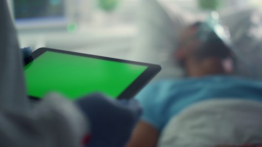 医务人员在医院特写镜头中拿着绿屏平板电脑检查病人状况视频