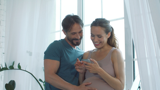 丈夫陪着怀孕的妻子一起看手机视频