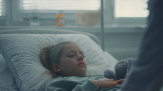生病小女孩躺在医院的床上拥抱玩具视频