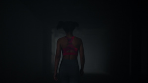 走在黑暗的走廊的女性运动员背影26秒视频