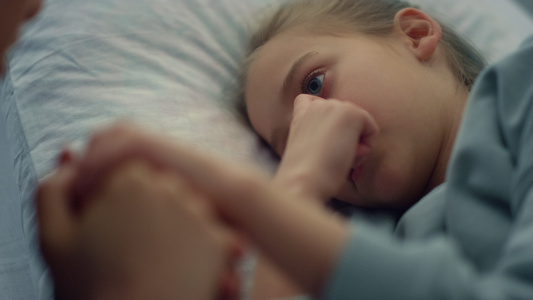 可爱的女孩躺在医院的病床上母亲轻轻地握着孩子的手特写视频