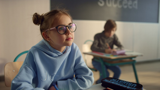 戴眼镜小女孩学生坐在课桌前认真听课视频
