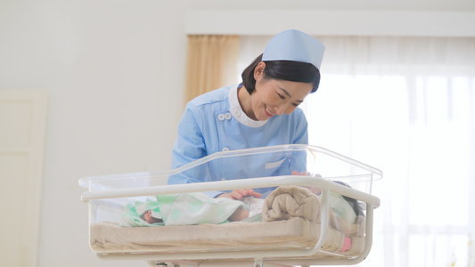 4k医院年轻的护士照看婴儿车里婴儿视频