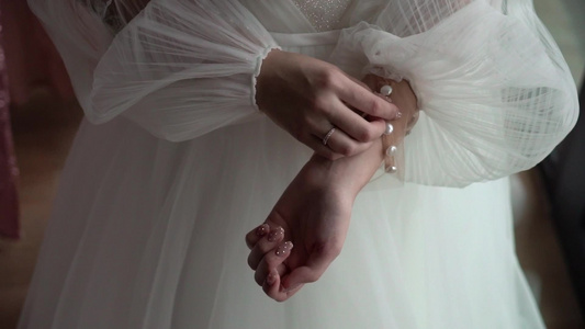 新娘在她的婚纱上扣上袖子穿上婚纱穿上礼服视频