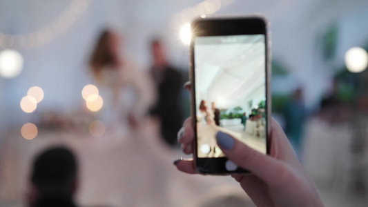 年轻夫妇的婚礼舞蹈新娘和新郎在帐篷派对上跳舞用手机视频