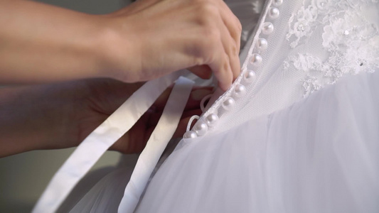 帮助年轻新娘穿上结婚礼服的伴娘视频