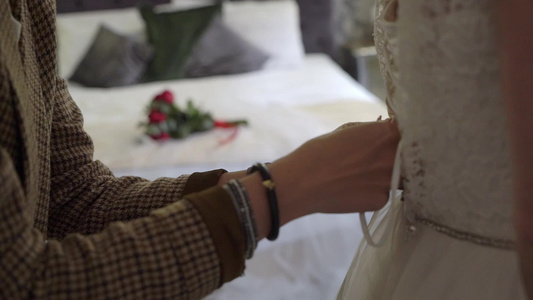 帮助年轻新娘穿上结婚礼服的伴娘奢华的婚纱视频