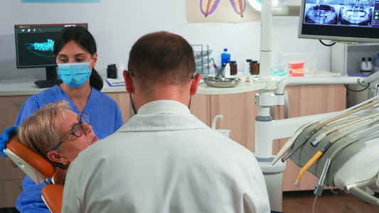 在现代牙科诊所与病人一起工作的牙医和助理人员视频