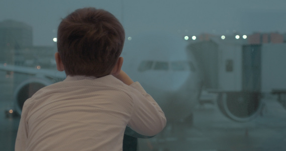 好奇的男孩在等待飞行时正在飞机上看着视频