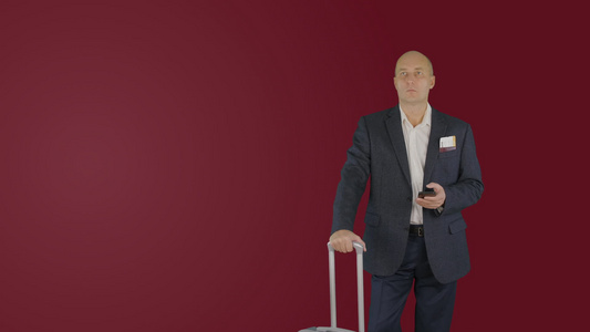 旅行商人行李箱在红色背景下看手机的手提箱视频