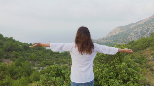 旅行的女人在雾山中享受早晨的风景旅游女人在山边伸手视频