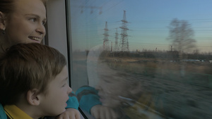 小男孩和母亲坐在火车上的窗户上看着外面21秒视频