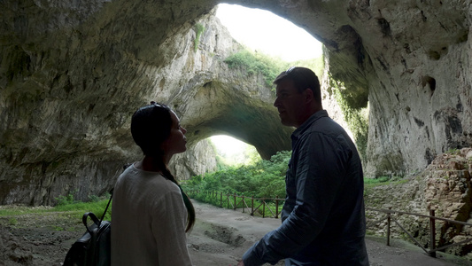 一对夫妇看着山上的一个大洞穴视频