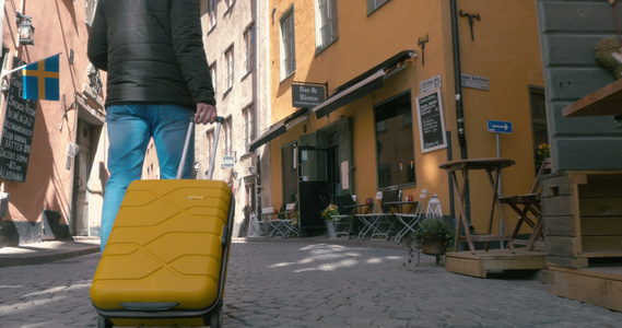 一个旅行者带着手提箱走在背面的景象视频