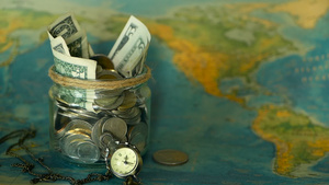 旅行预算概念在世界地图背景的玻璃罐中为假期节省的钱9秒视频