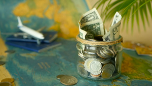 旅行预算概念在世界地图背景的玻璃罐中为假期节省的钱12秒视频