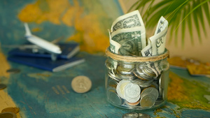旅行预算概念在世界地图背景的玻璃罐中为假期节省的钱22秒视频