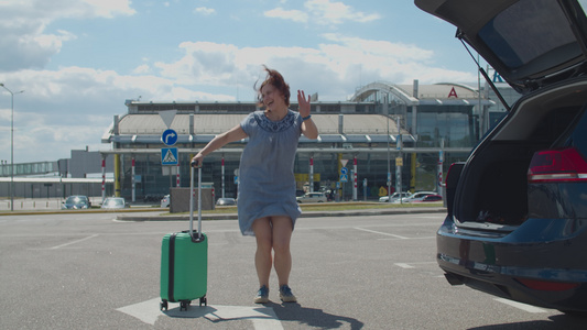 年轻快乐的女人独自带着手提箱在机场大楼附近跳舞女游客视频