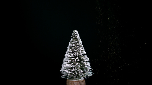 白雪覆盖的圣诞树在周围旋转闪亮的雪落下视频