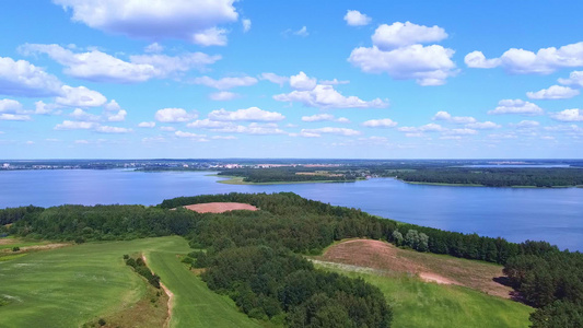 向着蓝湖和蓝天空的绿地上进行空中摄影视频