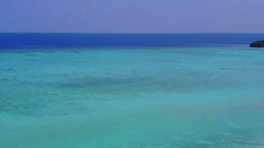 蓝色泻湖和白沙背景下宁静度假村海滩航行的无人机空中视频