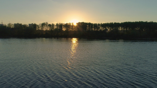 低角度飞向湖的右侧在公园中与太阳相对阳光照耀在树上视频