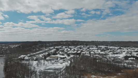 无人驾驶飞机的录像飞越小镇附近树木覆盖着积雪屋顶房屋视频