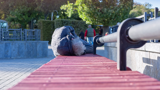 穷人躺在城市公园的板凳上视频