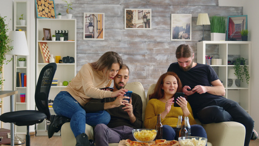 一群朋友用智能手机坐在沙发上坐着视频