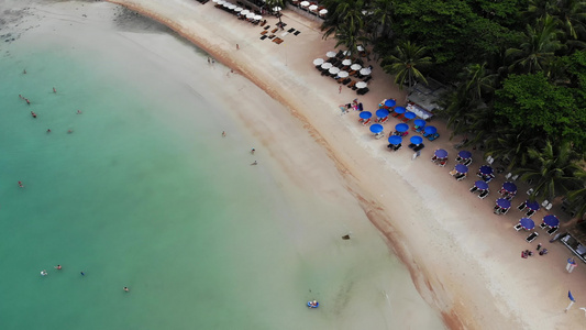 海滩上有许多配对的遮阳休息者在荒凉海滩上用雨伞和干净视频