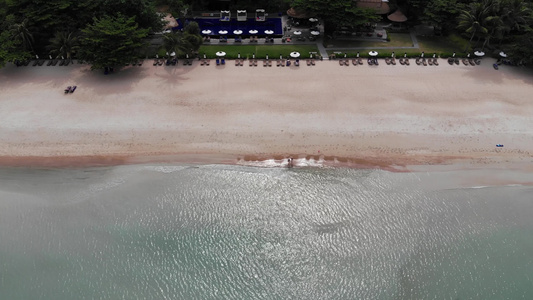 海滩上有许多配对的遮阳休息者在荒凉海滩上用雨伞和干净视频