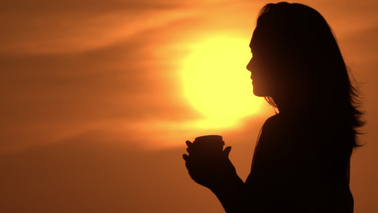 女人拿着杯子去喝太阳在天上升起视频