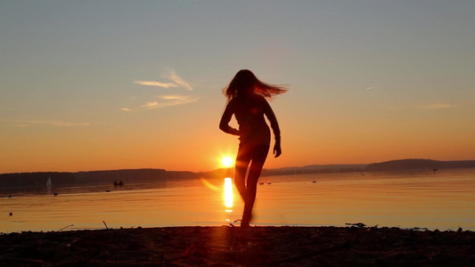 女孩在黄昏的夜晚海滩上跳舞视频
