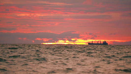 暗海和日落天空的红云上停靠货轮视频