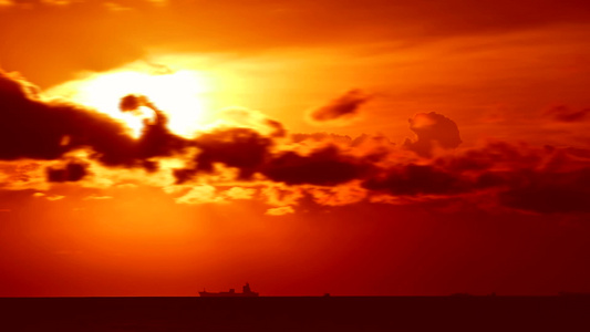 日落橙红色天空和暗红云在海上移动停靠货船停泊视频