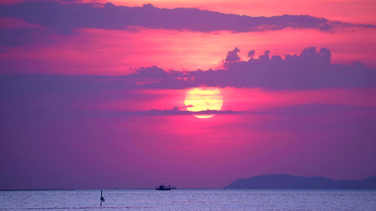 夕阳和紫云在海面上的天空和水面上的小波浪移动的渔船视频