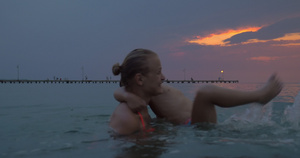 日落时妈妈和儿子在城市的海中游泳15秒视频