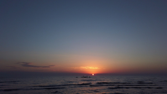 海滩上的日落海中岩石上的浅影渔民视频