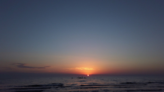 海滩上的日落海中岩石上的浅影渔民视频