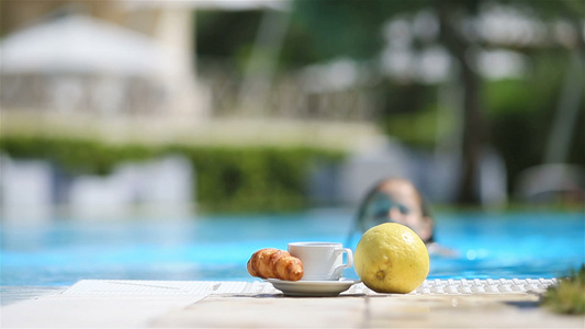 美味的早餐柠檬咖啡羊角面包在游泳池旁边视频
