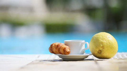 美味的早餐柠檬咖啡羊角面包在游泳池旁边视频