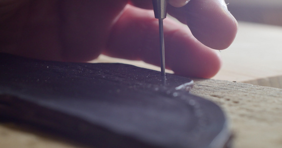 工匠手在一块天然皮革上打孔的电影特写镜头男人做手工视频